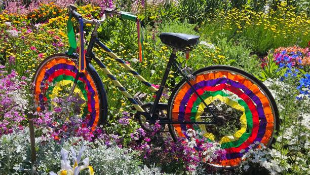 Bicycle art piece decorated with colored streamers in a garden full of flowers