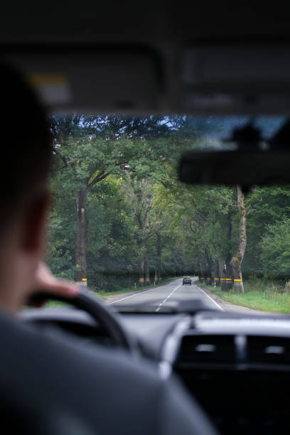 istock Man driving a car through a forest road 2182209356