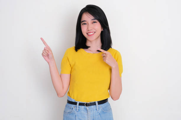 istock A young woman smiling at the camera while pointing beside her 2182210820