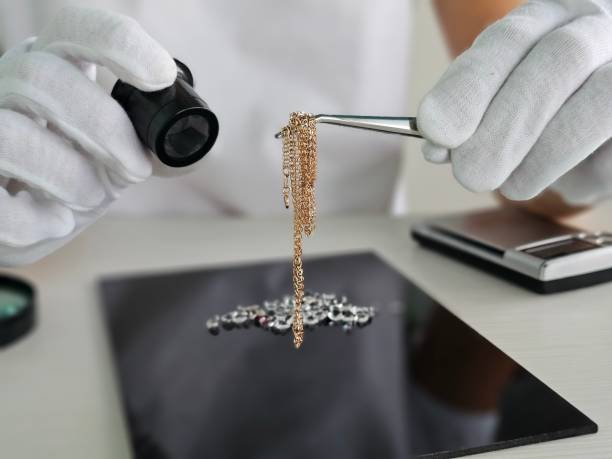 istock Jewelry appraiser examining a delicate gold chain with precision tools in a well-lit office 2182213493