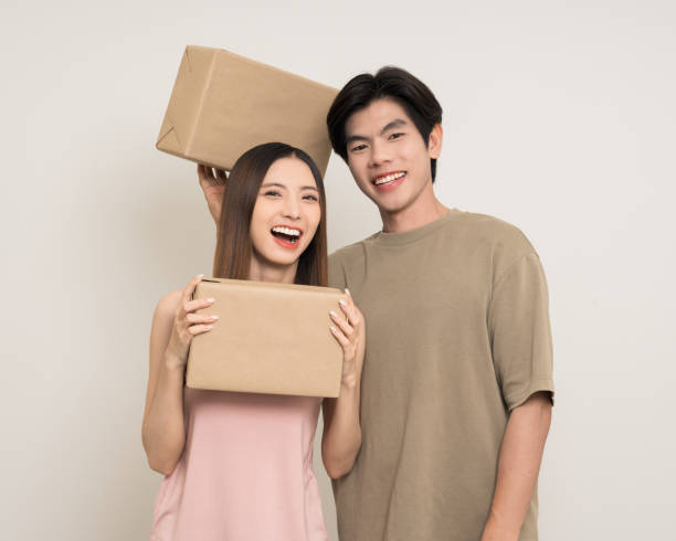 istock Happy asian couple attractive in various action gesture receive the parcel box cardboard delivery on isolated white background. Cheerful Smiling young man and woman holding box parcel of moving house 2182215820
