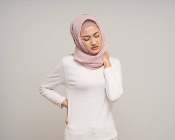 istock Unhappy young asian muslim woman has problem with structural posture neck and shoulder pain standing on isolated white background. Muslim woman wearing abaya and hijab has bad posture 2182216083