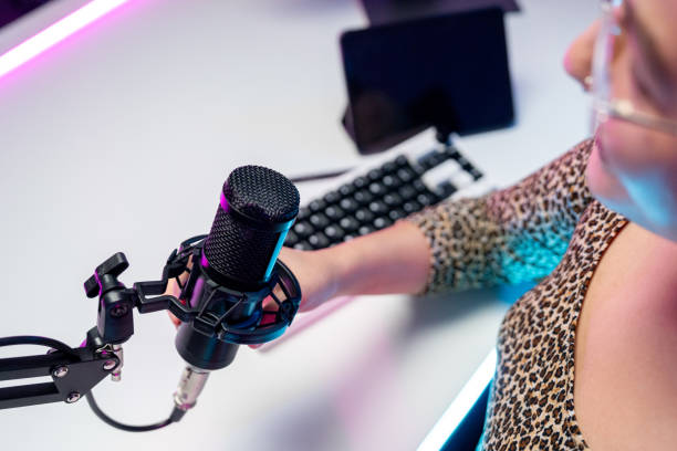 istock Content creator woman host streaming her a podcast with headphones and microphone interview cheering guest conversation broadcast studio with neon light. Blogger motivation recording voice over radio 2182216613