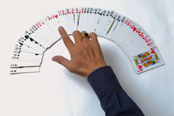 Magician's hand spreading out deck of cards on white table