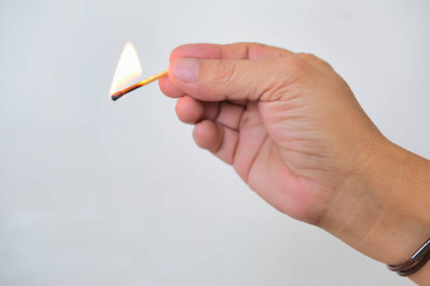 istock Hand holding a burning matchstick over white background 2182219101