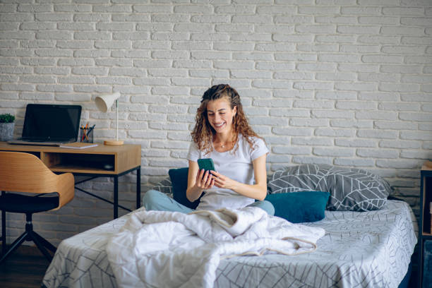 istock Woman in pajama using smart phone while relaxing on bed at home 2182222564