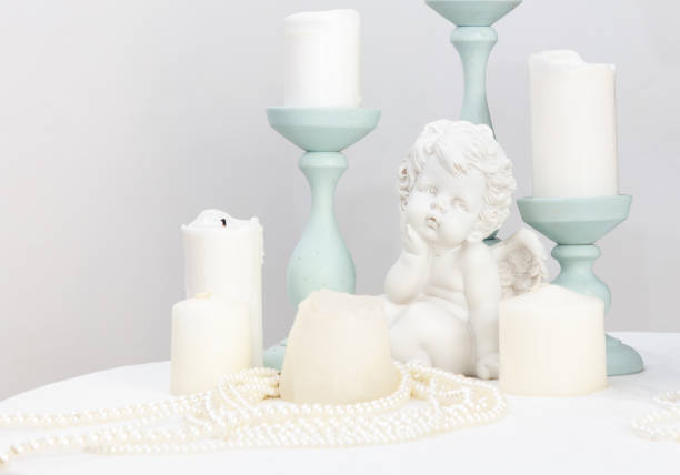 A white angel statue sits on a table with candles. Scene is serene and peaceful, as the candles
