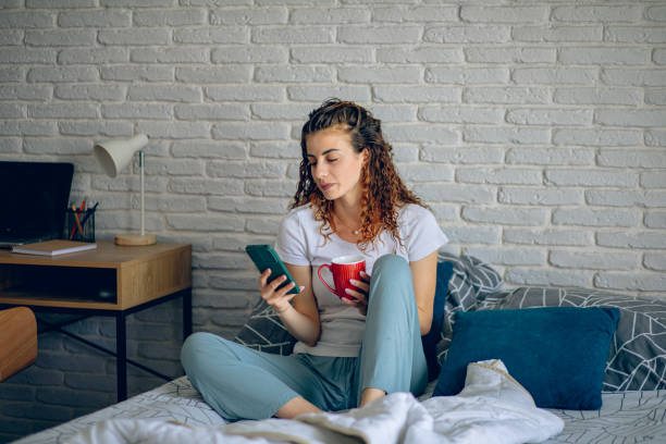 istock Woman in pajama using smart phone while relaxing on bed at home 2182222774