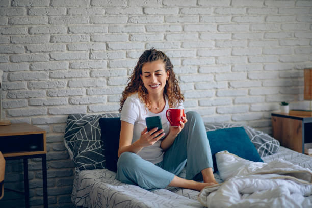 istock Woman in pajama using smart phone while relaxing on bed at home 2182223045