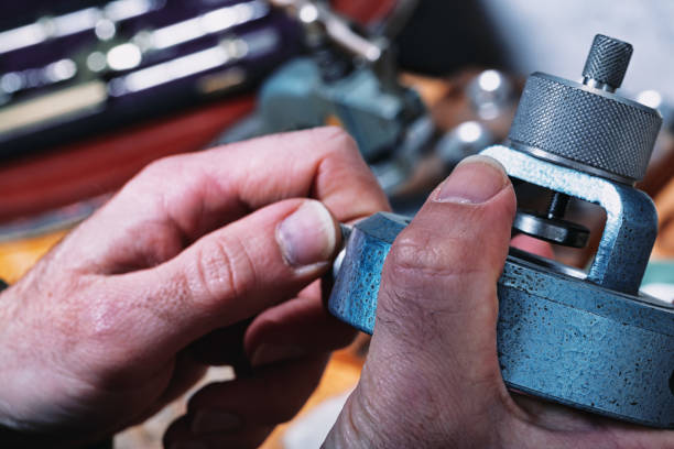 Close-up of watchmakers hands using a textured tool on a workbench. The precise grip and firm hold reflect the dexterity essential in handling tiny watch components