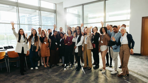 istock Diverse group at seminar happily waving inside modern conference room with large windows and bright natural light 2182230876