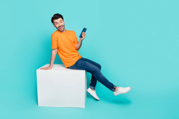 istock Full body profile side photo of excited guy sit white cube using gadget like posts isolated on cyan color background 2182233526