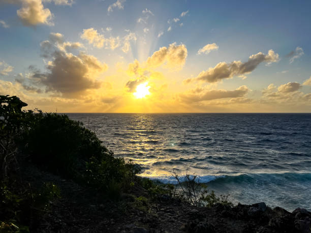 A dark sunset over tropical waters, with a soft orange glow fading into the dim evening sky