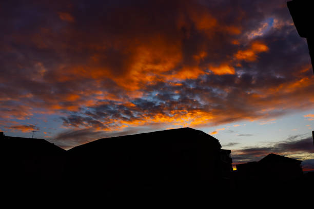 Beautifully golden colored clouds at dusk contrasting with the light blue sky above the city silhouette