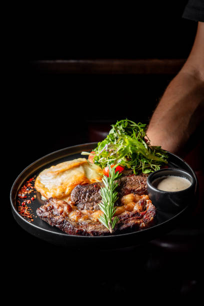 istock A gourmet steak dish served on a dark plate, garnished with fresh herbs and accompanied by side dishes. Perfect for culinary themes, restaurant promotions, or food photography. 2182243119