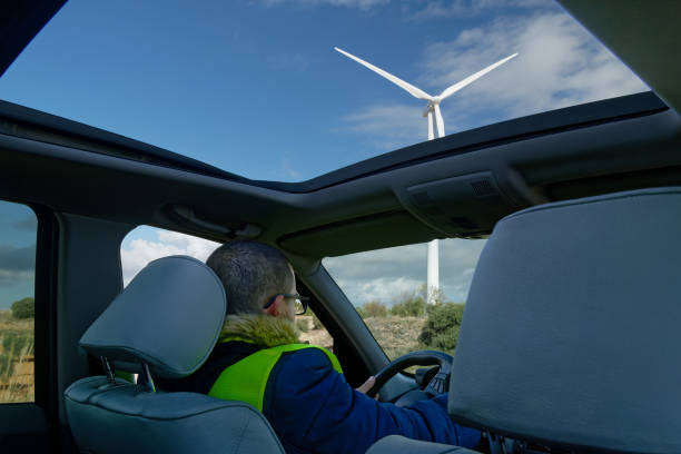 istock Technician driving car watching wind turbine through open sunroof 2182244702