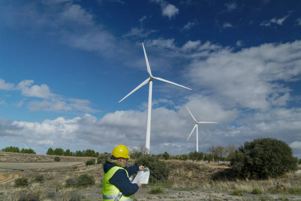 istock Wind turbine engineer inspecting blueprints in a wind farm with cloudy sky 2182244722