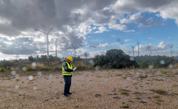 istock Engineer inspecting wind turbines in a wind farm under cloudy sky 2182244793