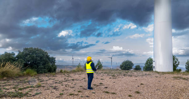 istock Engineer inspecting wind turbines in a wind farm under cloudy sky 2182244818