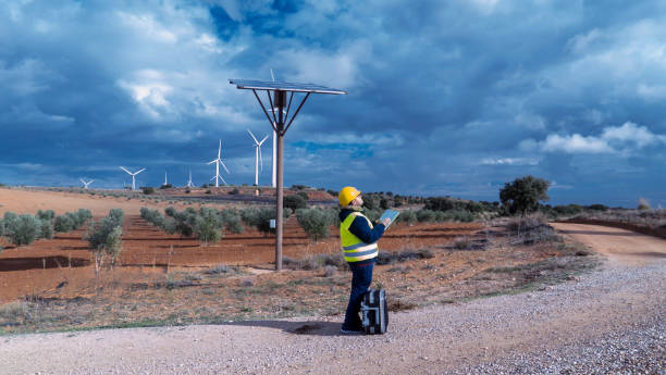 istock Technician inspecting solar panel and wind turbines in sustainable energy farm 2182245040