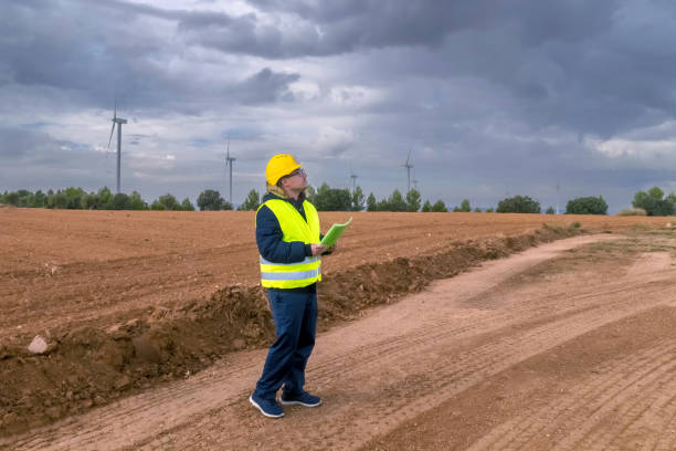 istock Female engineer inspecting wind turbines in a field with cloudy sky 2182245089