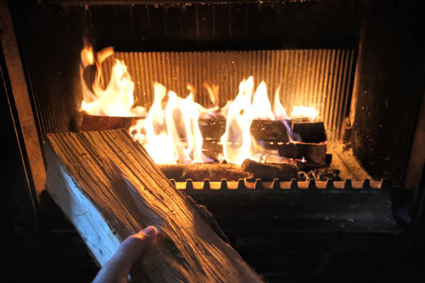 istock A log, held in a man's hand, about to be placed in a fireplace 2182245926