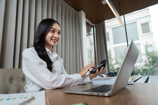 istock Young Professional Woman Working on Laptop and Smartphone in Modern Office Setting 2182246013