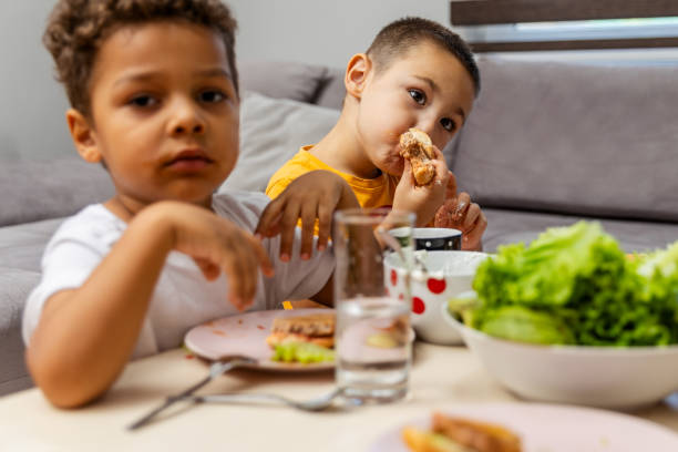 istock Two young boys eating sandwiches at dining table. 2182246357