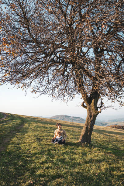 Mother and the son spending day in nature. They are sitting on the grass and playing