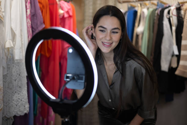 istock Fashion blogger using smartphone and ring light to create content in a clothing store 2182253321