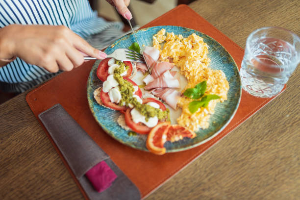 istock Woman having delicious breakfast with scrambled eggs and bruschetta in restaurant 2182255002