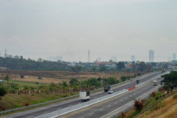 istock A serene toll road with light traffic, surrounded by lush greenery and distant cityscape under a hazy sky. Ideal for travel, transportation, and urban rural contrast themes 2182256232