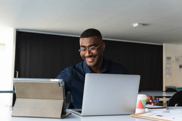 istock Black guy video chatting on tablet near laptop in workplace 2182256488