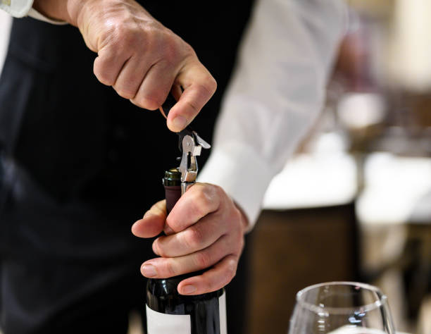 istock Waiter opening red wine bottle with corkscrew in restaurant 2182260494