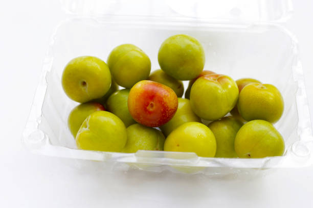 Ripe purple plums of the Ugorka variety in a transparent glass plate on a white background