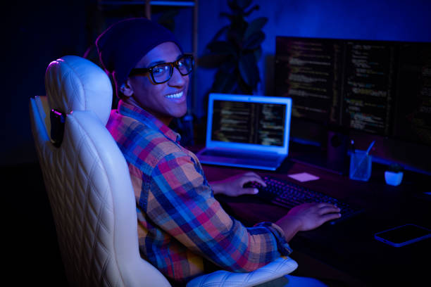 istock Profile portrait of cheerful hacker guy sitting chair keyboard typing operating database night loft room indoors 2182261164