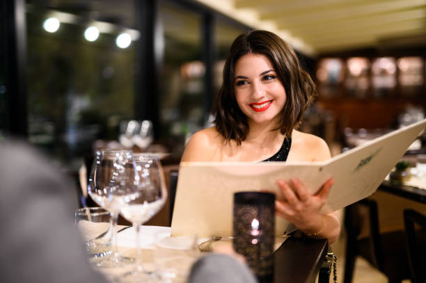istock Elegant woman smiling and reading menu in a restaurant 2182261192