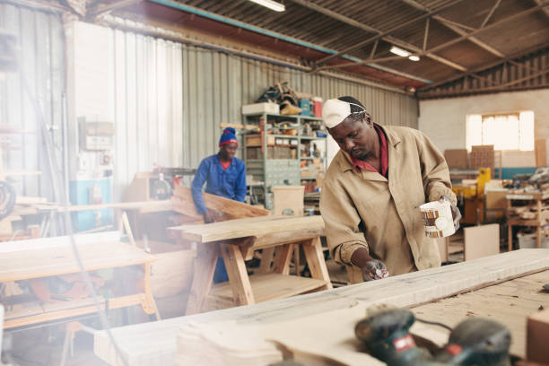 istock An ethnic carpenter painting a plank with varnish 2182263498