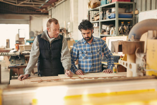 istock Two serious carpneters looking at a plank in their workshop 2182263774