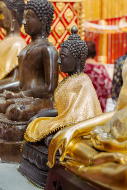 istock Buddhist statues adorned with golden robes in a temple. 2182283295