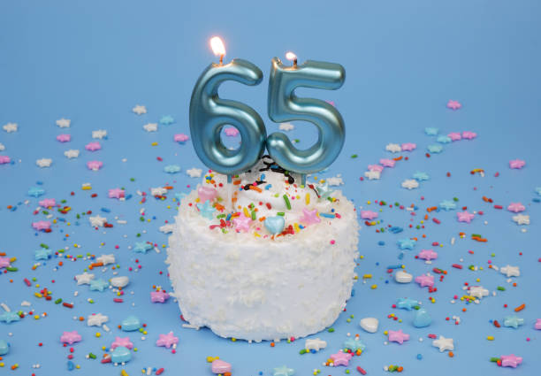 istock Coconut birthday cake on blue background with burning candle, number 65 2182286509