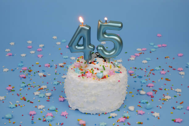 istock Coconut birthday cake on blue background with burning candle, number 45 2182286531