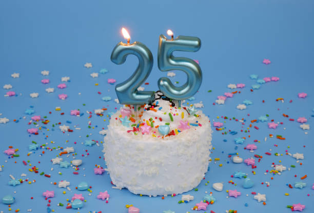 istock Coconut birthday cake on blue background with burning candle, number 25 2182286539