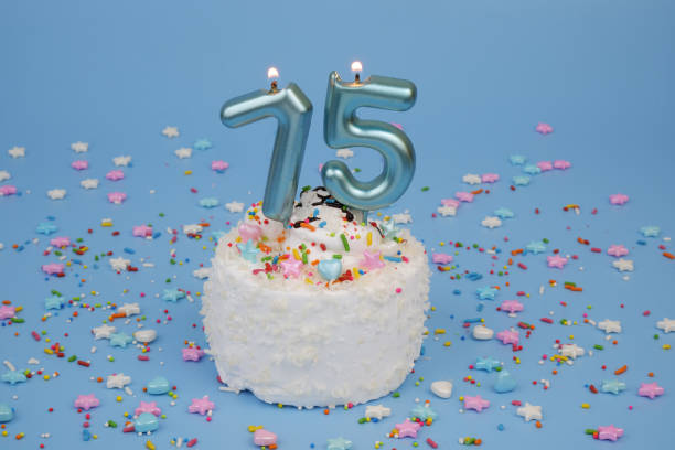 istock Coconut birthday cake on blue background with burning candle, number 75 2182286566