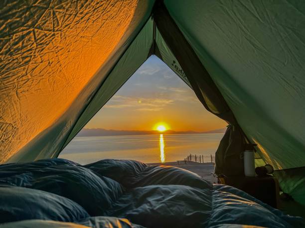 istock Scenic view from a tent overlooking a serene sunrise over a calm lake 2182288643