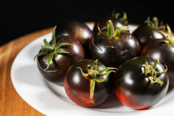 Cumato black tomatoes in a white plate. Black tomato..