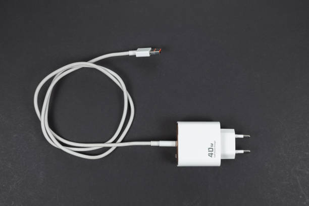 white smartphone charger on dark background. Charger and USB cable type C on dark background white smartphone charger on dark background. Charger and USB cable type C on dark background. phone charger cable stock pictures, royalty-free photos & images