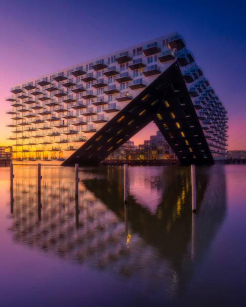 Amsterdam, Netherlands. Cityscape during sunset. Reflection on the water surface. Apartment building near the water in the bay. Architecture of the Netherlands.