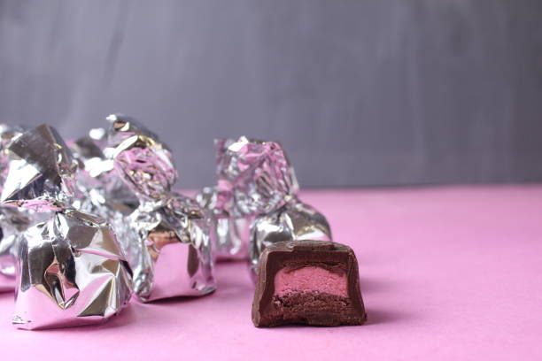 Silver-wrapped candies. Cut candy piece with pink filling praline taste raspberry strawberry.