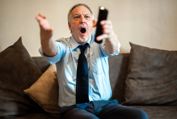 istock Excited mature businessman watching tv and changing channels on sofa 2182306784